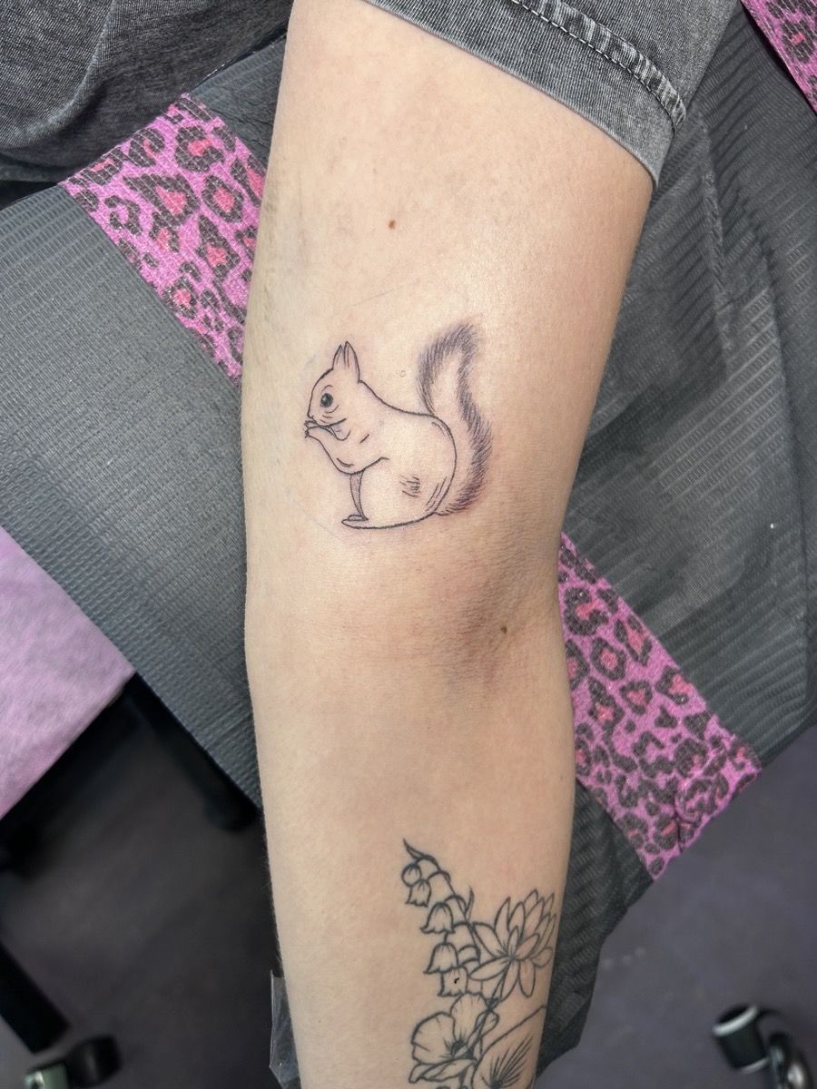 A fine-line squirrel with a bushy tail sitting upright, softly shaded, on a forearm